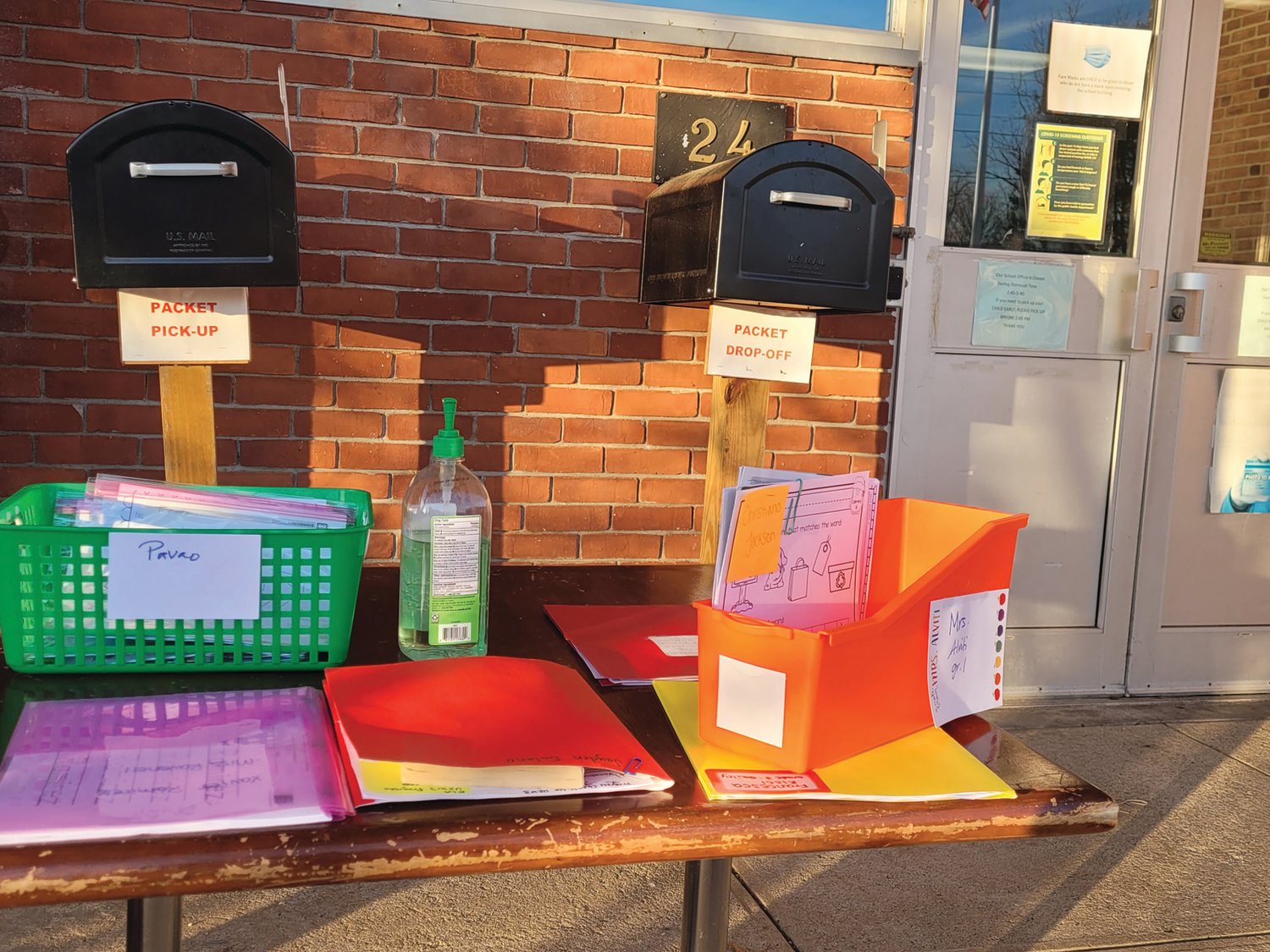 HOME WORK AWAITS: Packets of school work await students outside the main entrance to : Sarah Dyer Barnes Elementary School in Johnston, which has been closed for the week after a significant COVID-19 outbreak.